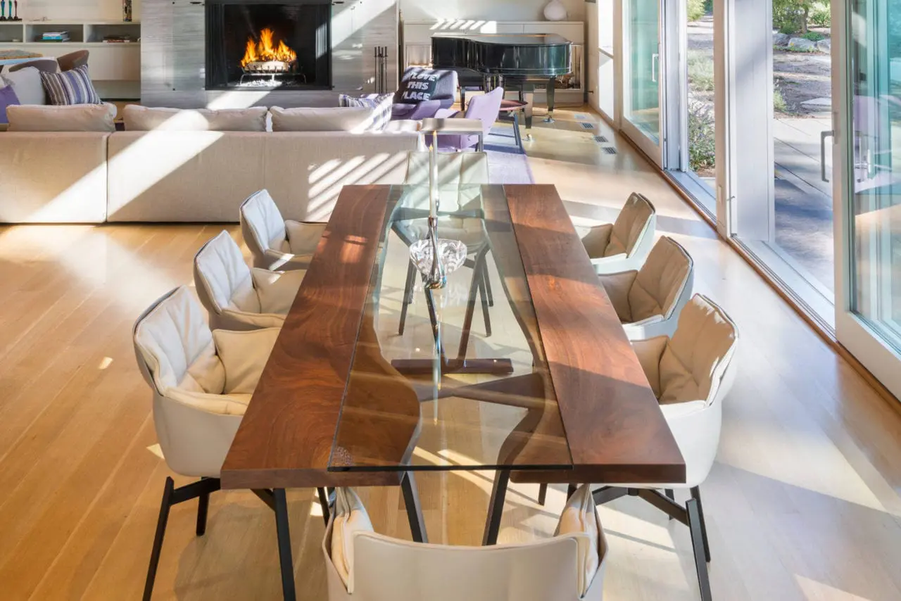 a custom SENTIENT contemporary designed walnut Colorado table with luxury chairs in an open designed room with fireplace