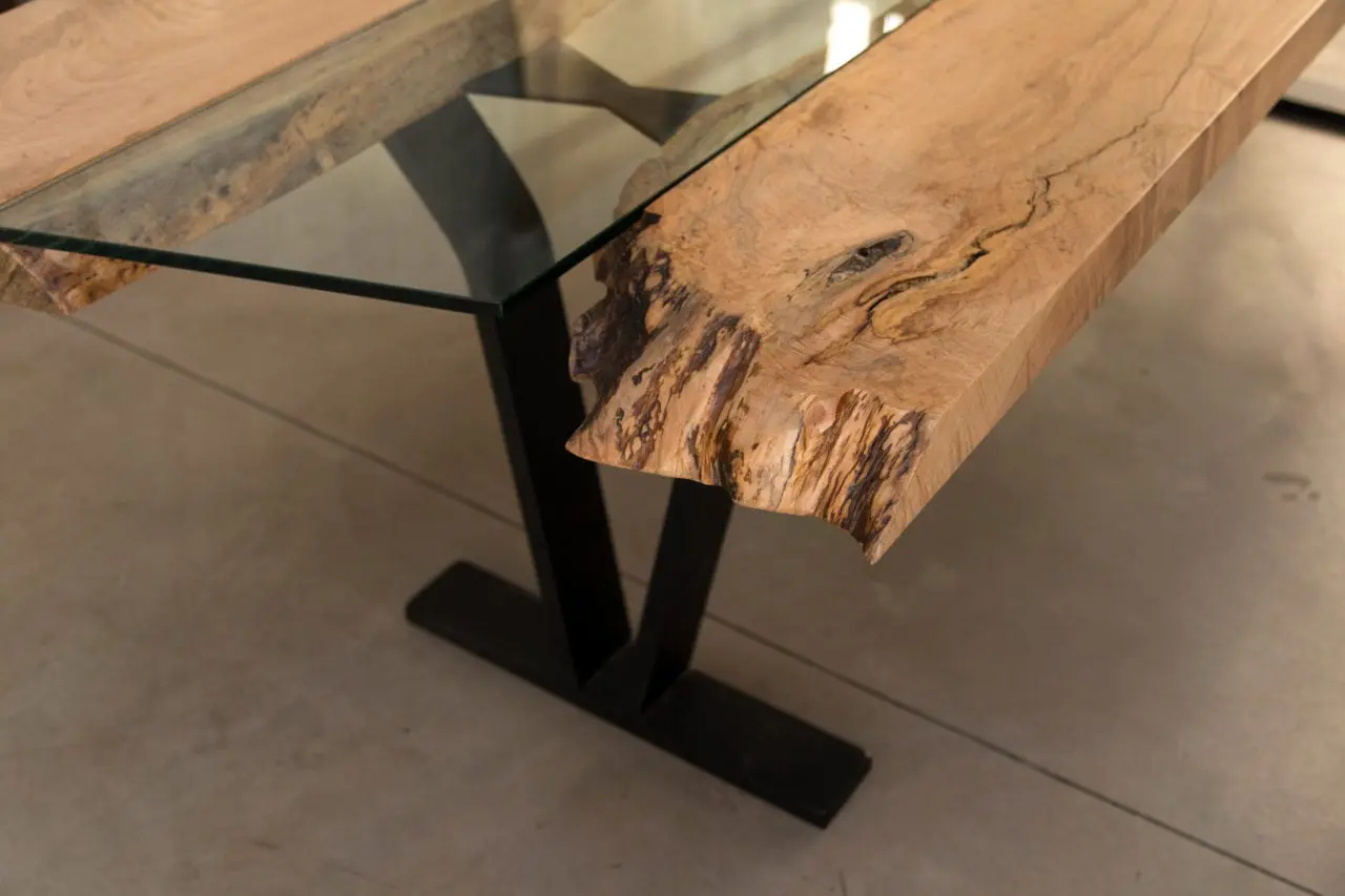 a SENTIENT contemporary designed Colorado table in maple with custom glass inset and blackened steel v shape leg detail view