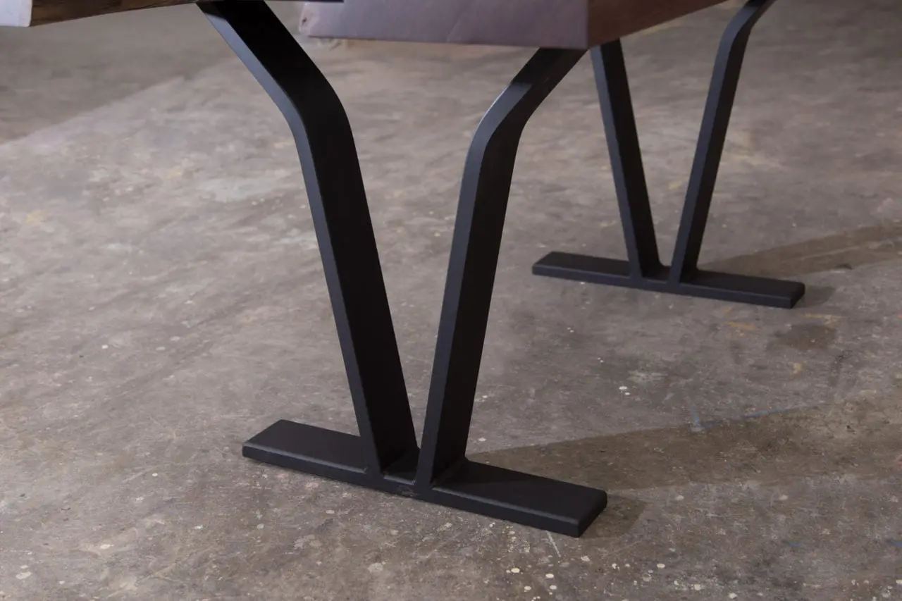 an american black walnut solid live edge luxury table detail with a pair of v-shaped blackened steel legs
