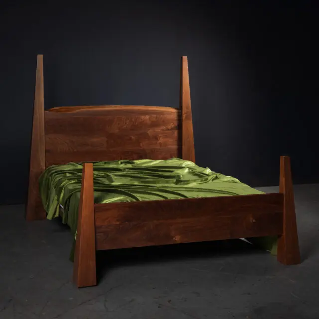 Citadelle bed crafted from rich walnut wood, showcasing angular tapered posts and a sleek minimalist design.