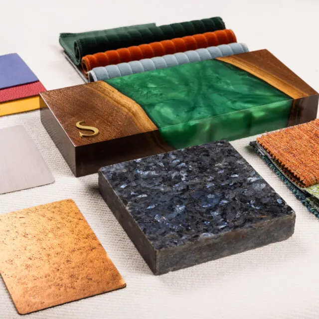 A curated display of material and finish options for SENTIENT furniture, featuring wood, resin, metal, fabric, and stone samples.