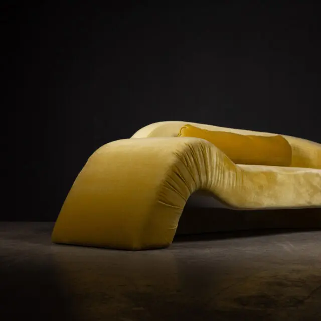 The SENTIENT Aeon Sofa in luxurious yellow velvet upholstery, featuring a sculptural and modern design with smooth curves and a bold aesthetic. Perfect for contemporary interiors with a statement-making style.