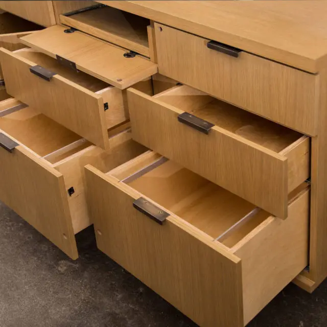 A bespoke oak credenza showcasing open drawers with sleek metal pulls, highlighting practical design and craftsmanship by SENTIENT.
