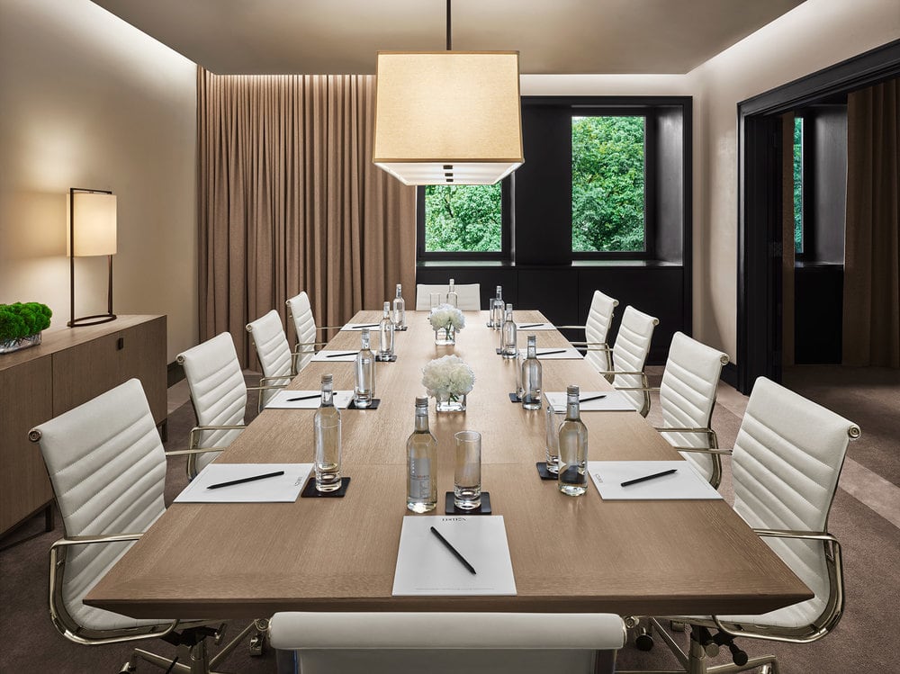 a SENTIENT designed custom conference table in walnut with white desk chairs in a New York edition hotel space