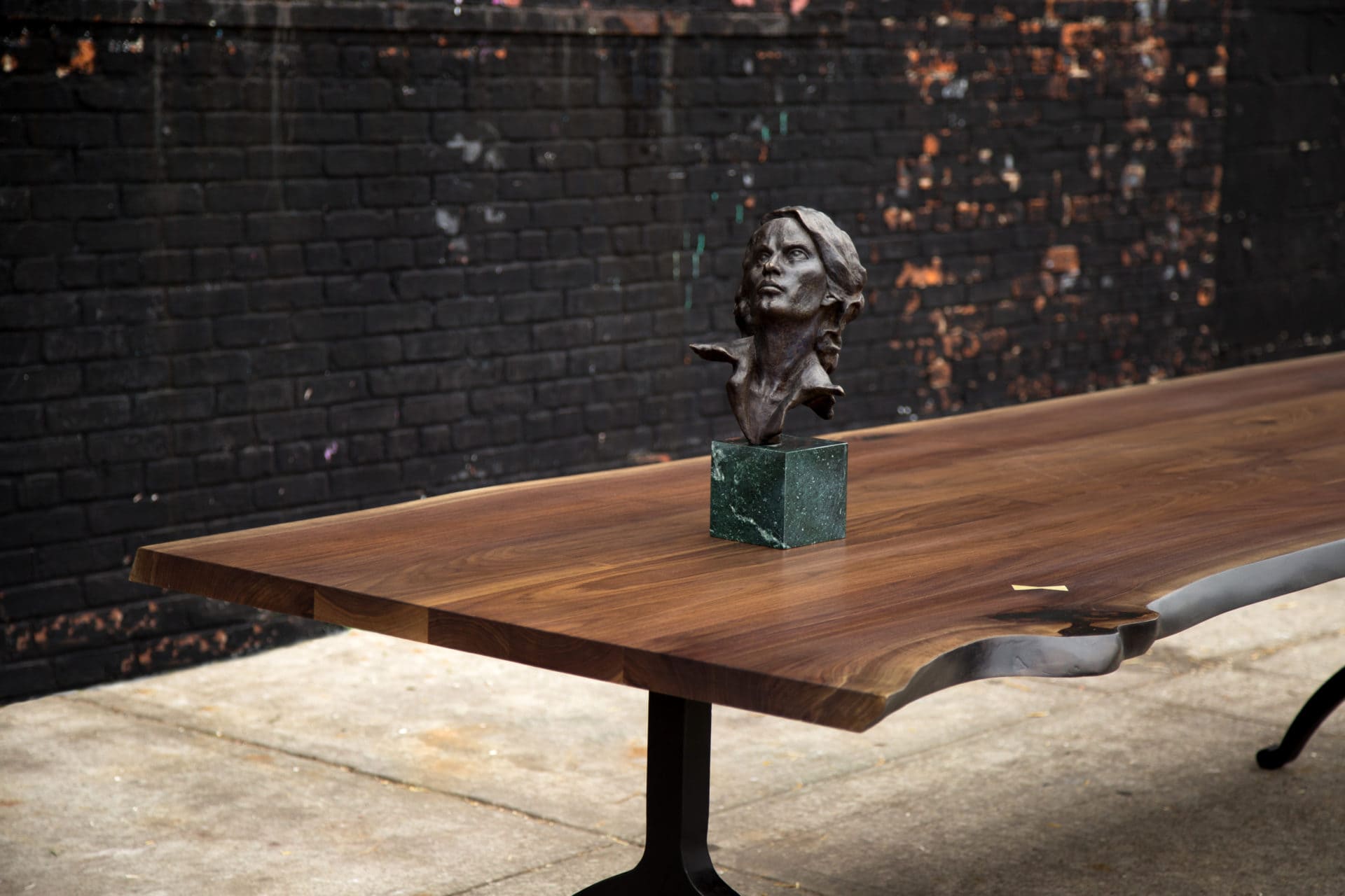 a contemporary designed SENTIENT walnut live edge wood luxury table detail with sculpted bust on top