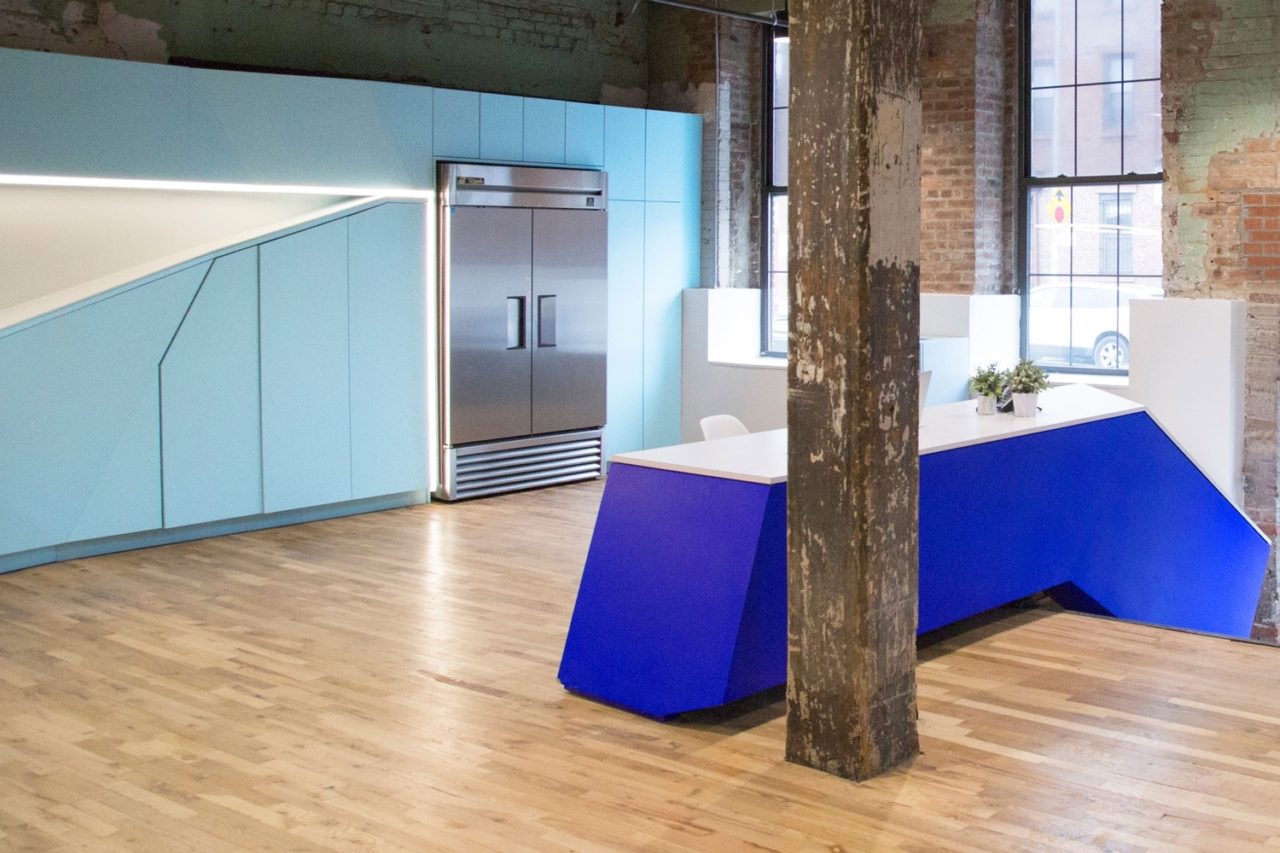 in a bond collective office SENTIENT contemporary designed custom furniture with a long low blue accented wall in kitchen area