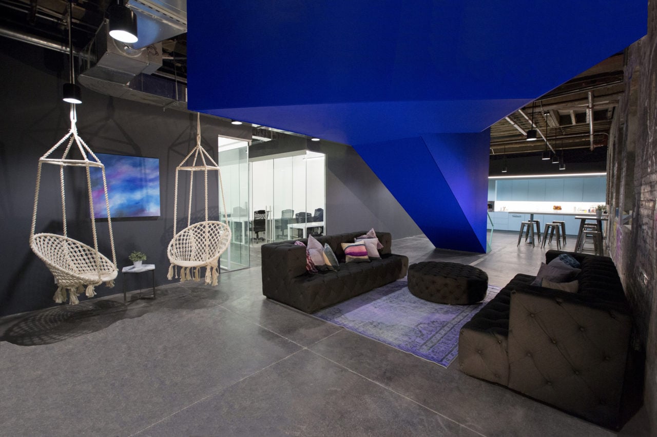 in a bond collective office SENTIENT contemporary designed custom tufted sofas and ottoman with a blue accented wall  
