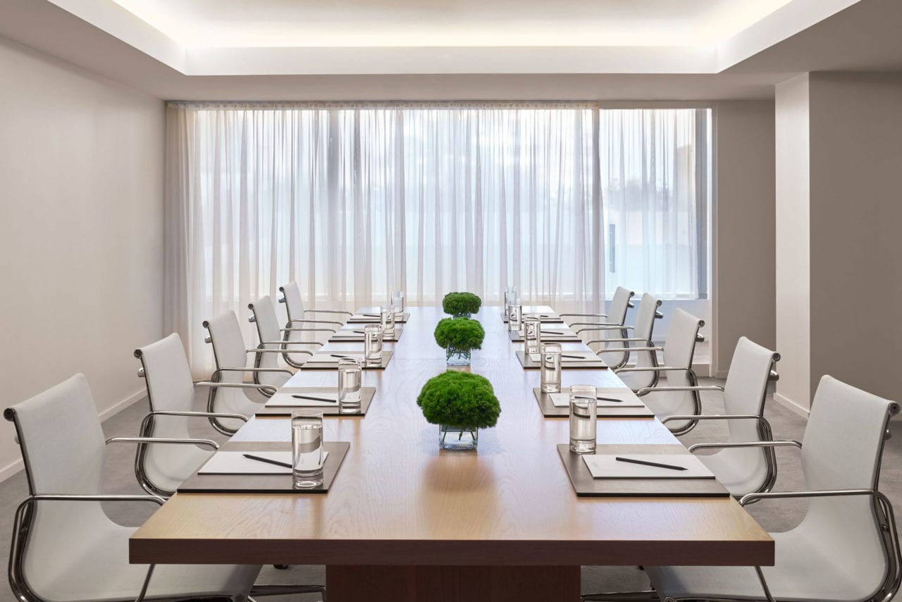 a luxury maple custom SENTIENT contemporary conference table in a Miami edition hotel with white chairs in a white space 