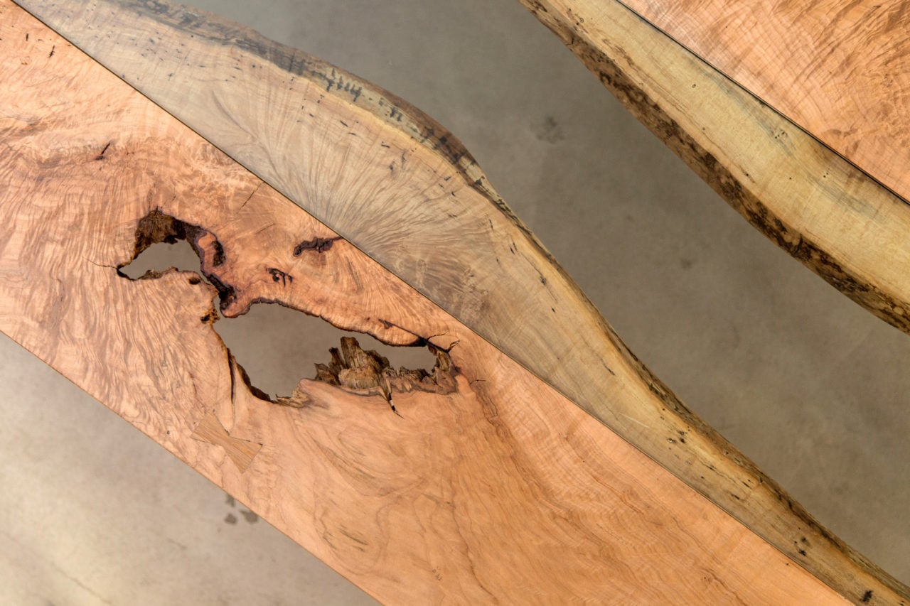 an arial detail view of a SENTIENT contemporary designed Colorado custom table in luxury maple with glass inset down the middle