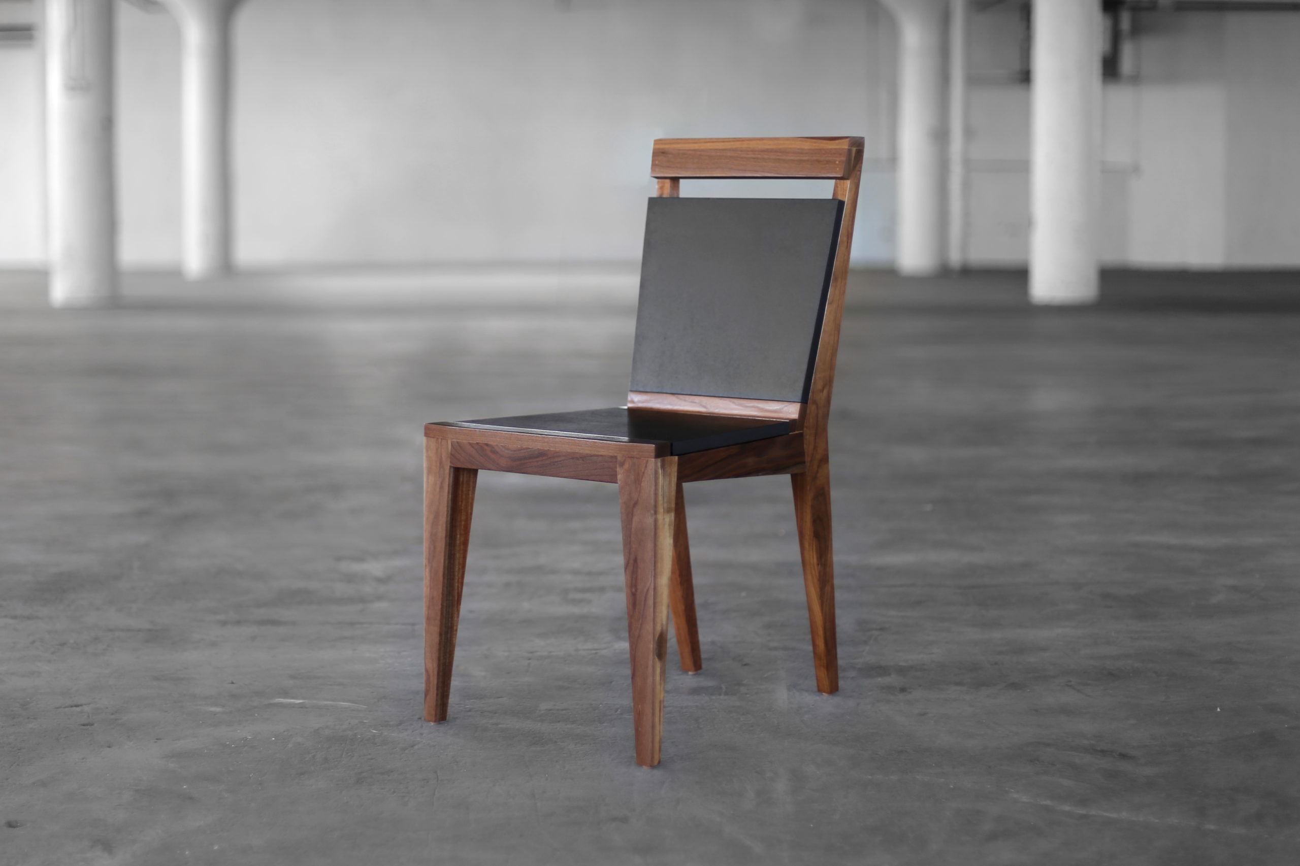 SENTIENT contemporary designed Angles dining chair in walnut with custom solid black back and seat side view in an open loft