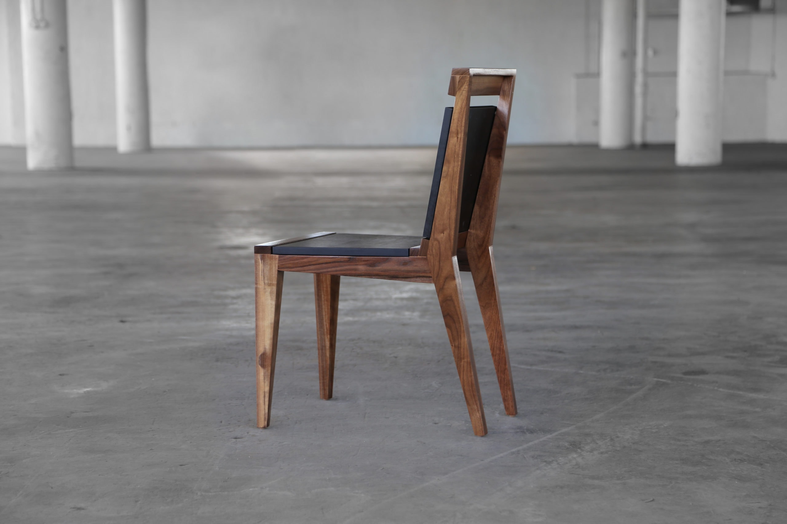 SENTIENT contemporary designed Angles dining chair in walnut with custom solid black back and seat side view in an open loft side view