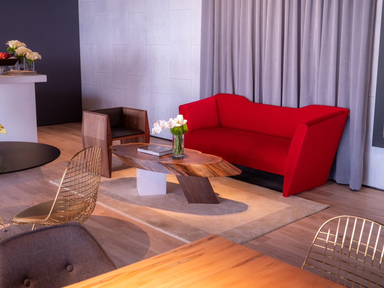 A contemporary designed SENTIENT custom nersi sofa in luxury red fabric and a live edge coffee table with a sapience chair