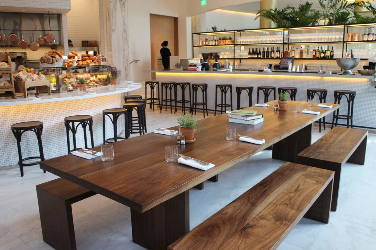 a custom SENTIENT contemporary designed communal walnut table with benches in a luxury Miami edition hotel restaurant 