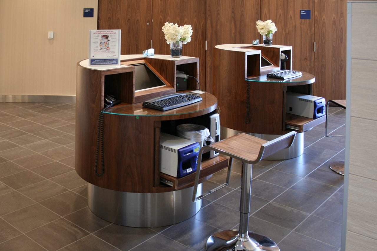 two custom SENTIENT contemporary designed round luxury wood desks in British airways terminal 