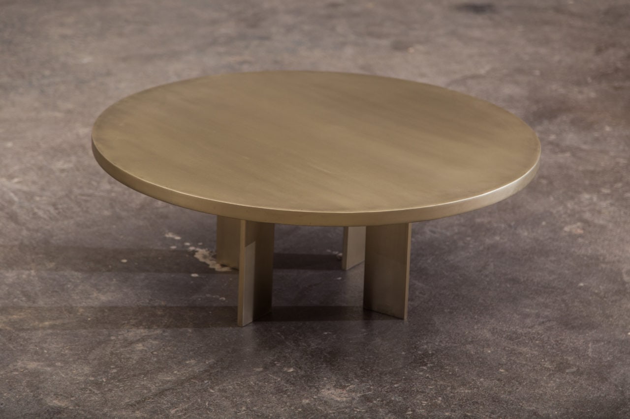 a contemporary designed round four legged luxury antique brass coffee table