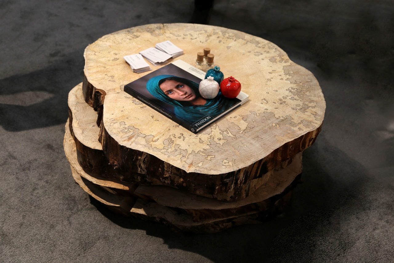 Four stacked round custom maple sliced SENTIENT contemporary designed solid wood coffee table with books and vases on top 