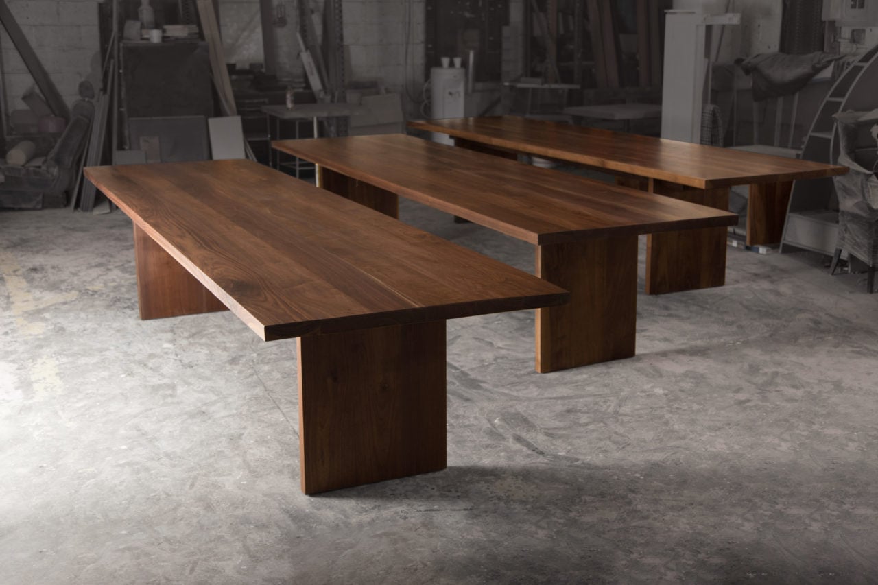 three SENTIENT contemporary designed custom walnut conference tables with plank bases in a workroom 