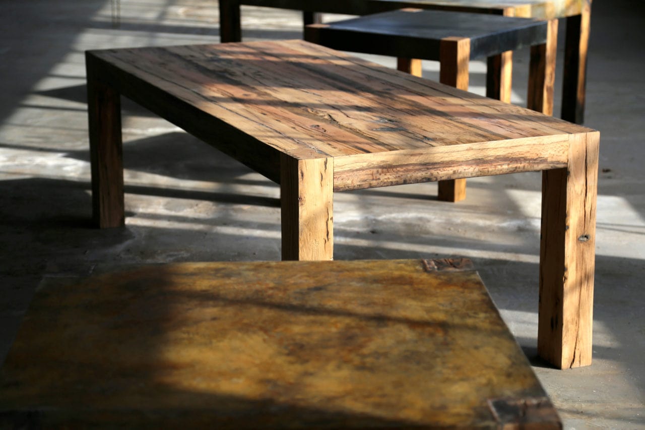 a room view of several custom reclaimed wood SENTIENT contemporary designed communal tables with shadows