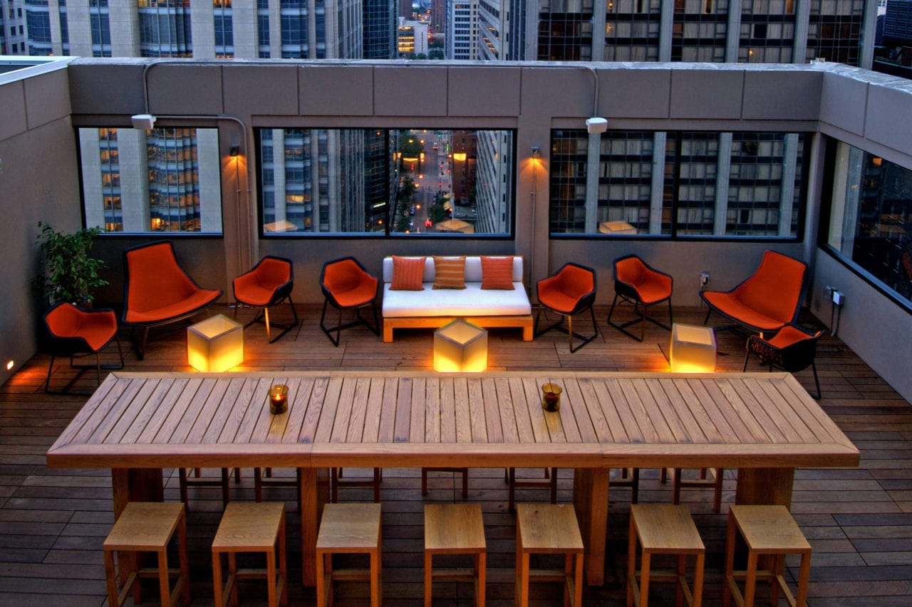 arial view of a long SENTIENT contemporary designed communal custom wood table at the Stewart hotel affinia rooftop lounge
