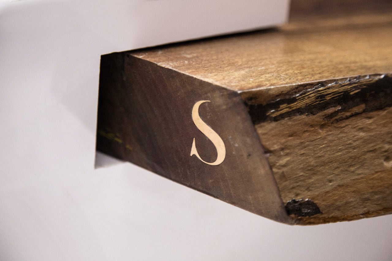 a brass letter S set into solid American walnut wood edge contemporary coffee table with luxury white base detail 