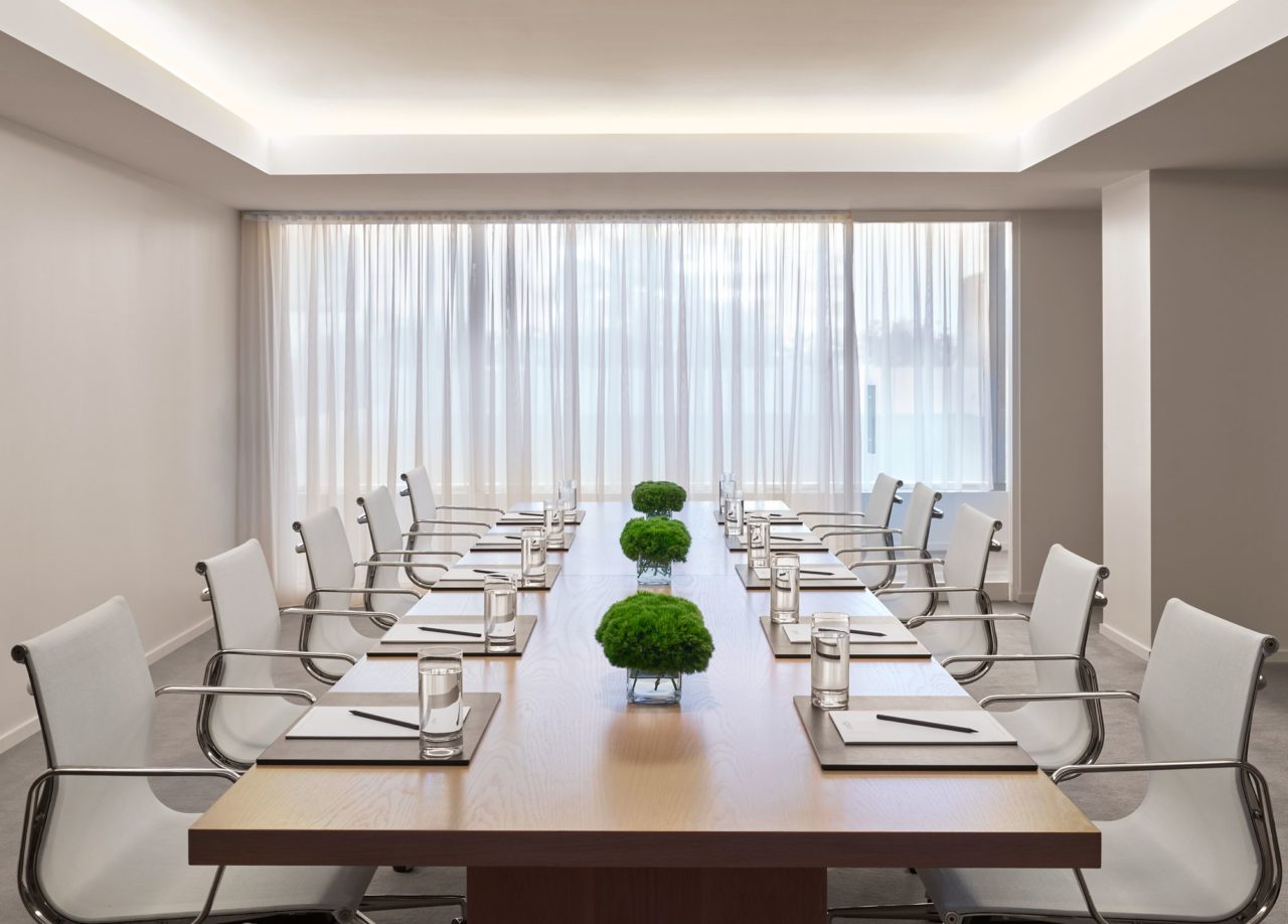 a luxury maple custom SENTIENT contemporary conference table with luxury white chairs in a white office 
