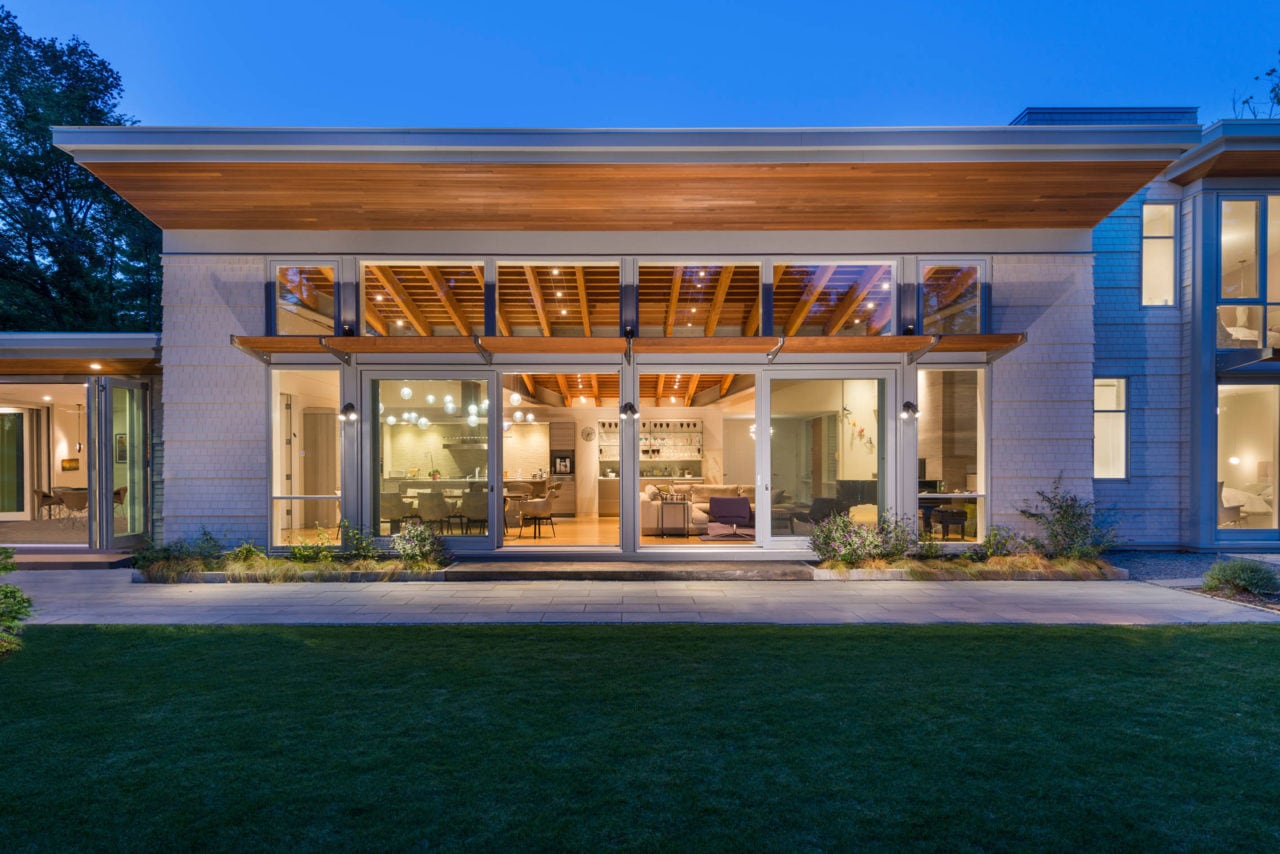 an outside view of a luxury home with large expanse of custom windows