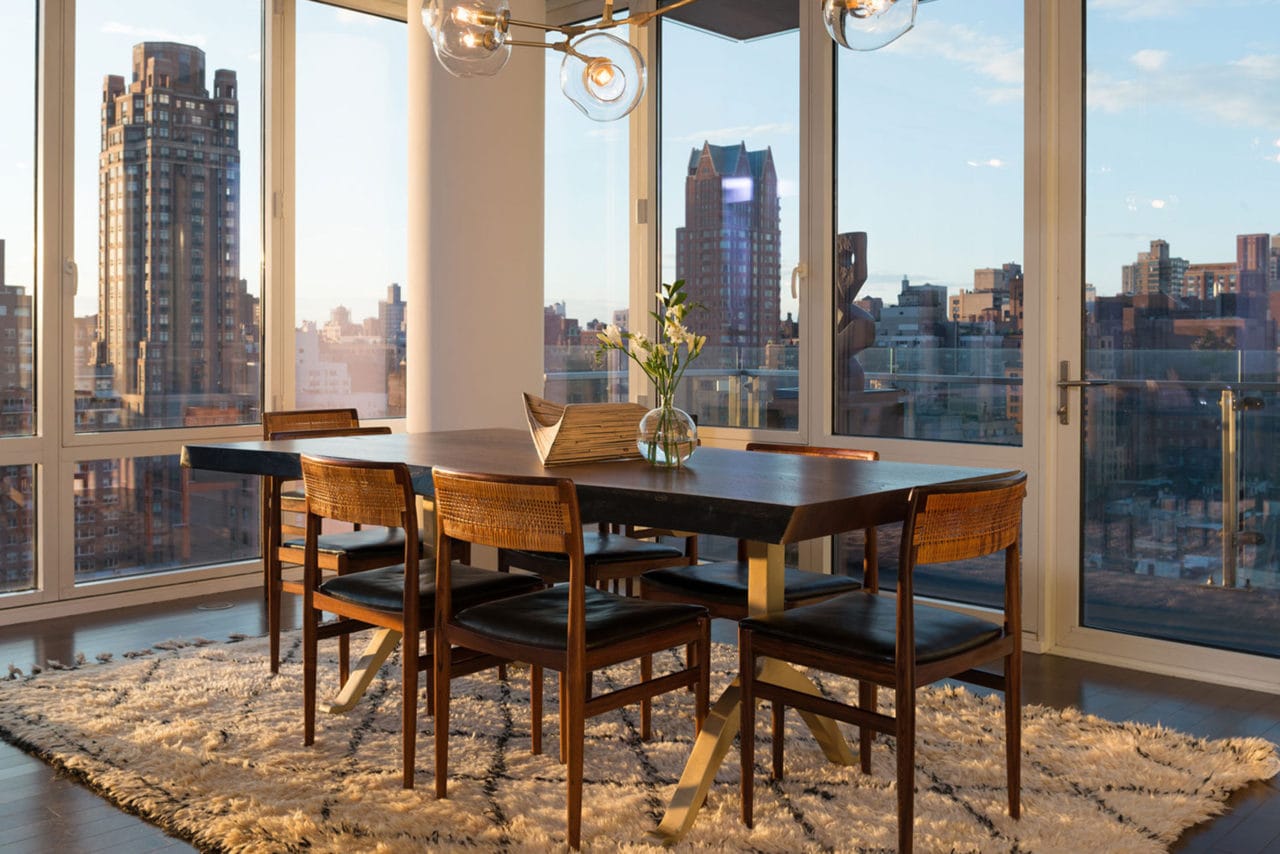 a high-end SENTIENT contemporary designed wood dinning table and luxury chairs in a window surrounded room