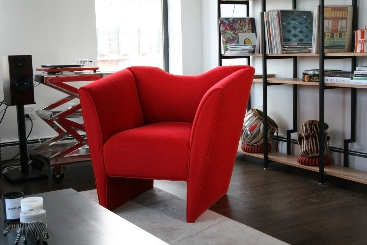 a contemporary designed SENTIENT nersi custom armchair in luxury red upholstery with bookcase in background 