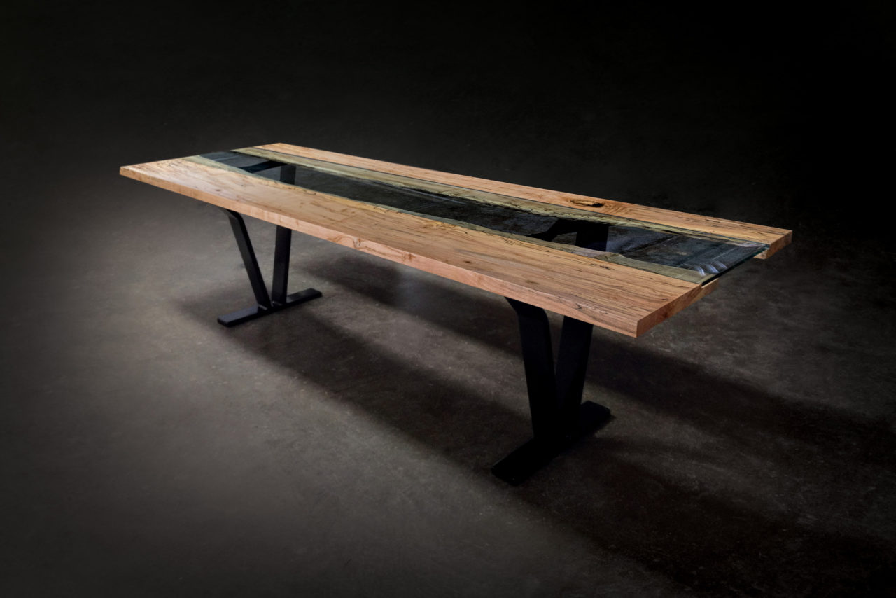 a SENTIENT contemporary designed Colorado ambrosia table in maple with custom glass inset and blackened steel v shape leg 