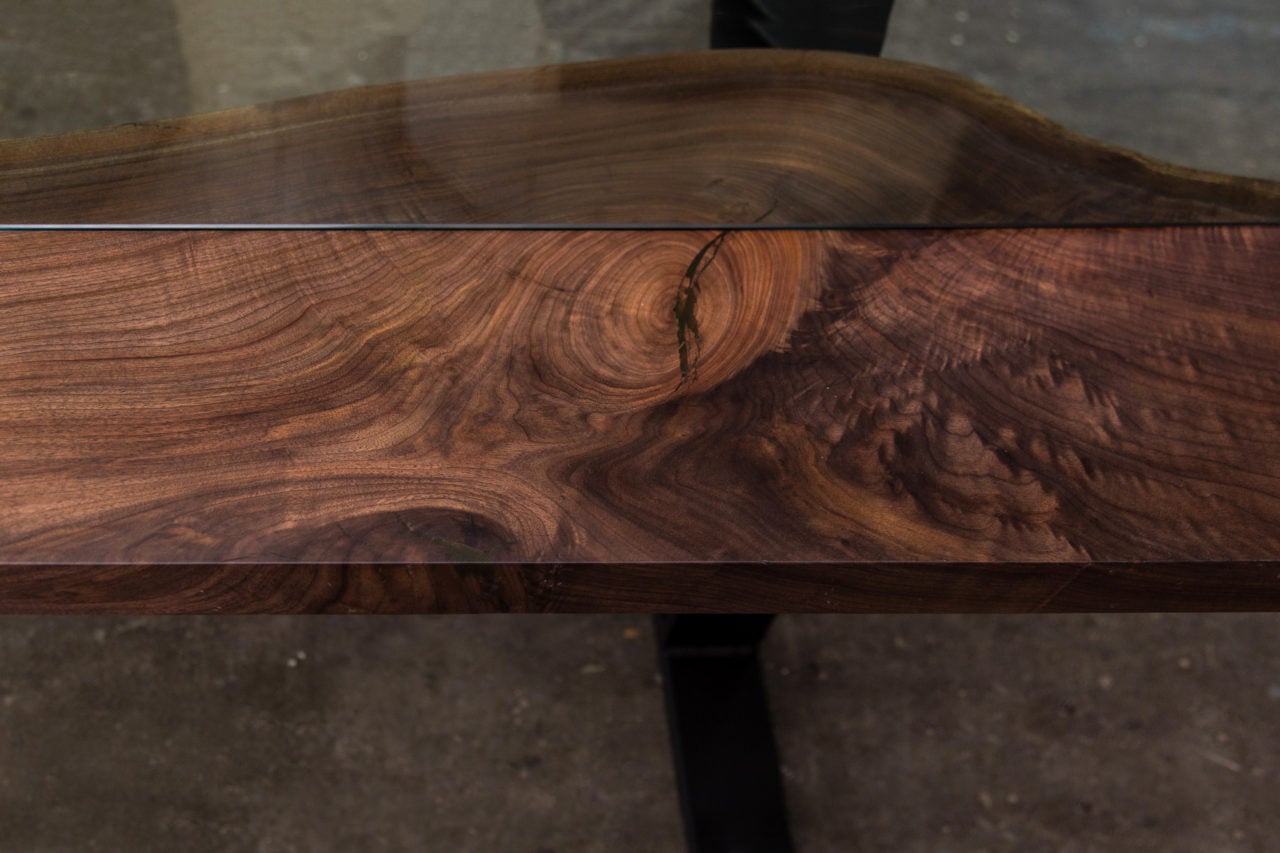 an arial detail view of a SENTIENT contemporary designed Colorado custom table in luxury walnut with glass inset down the middle