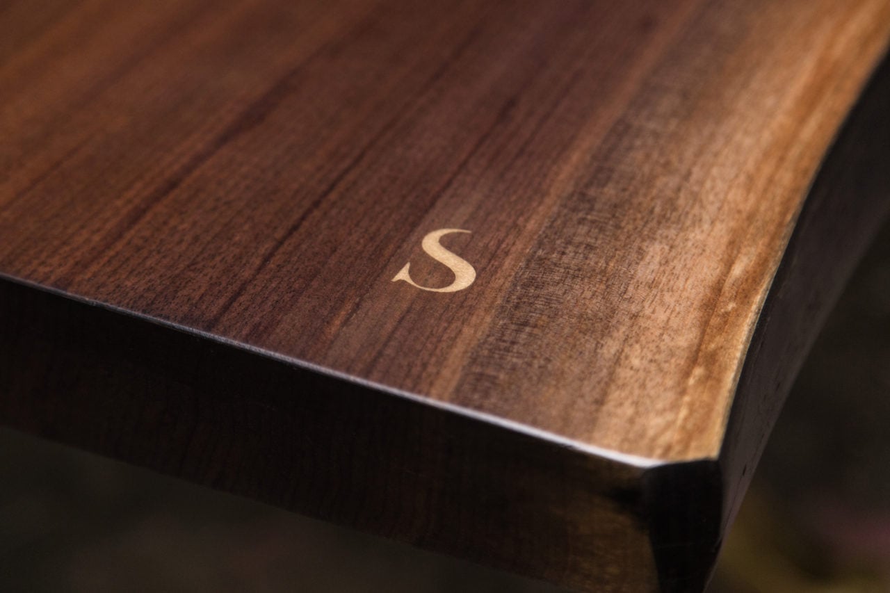 a live edge SENTIENT contemporary designed custom table corner detail with brass letter s inset 