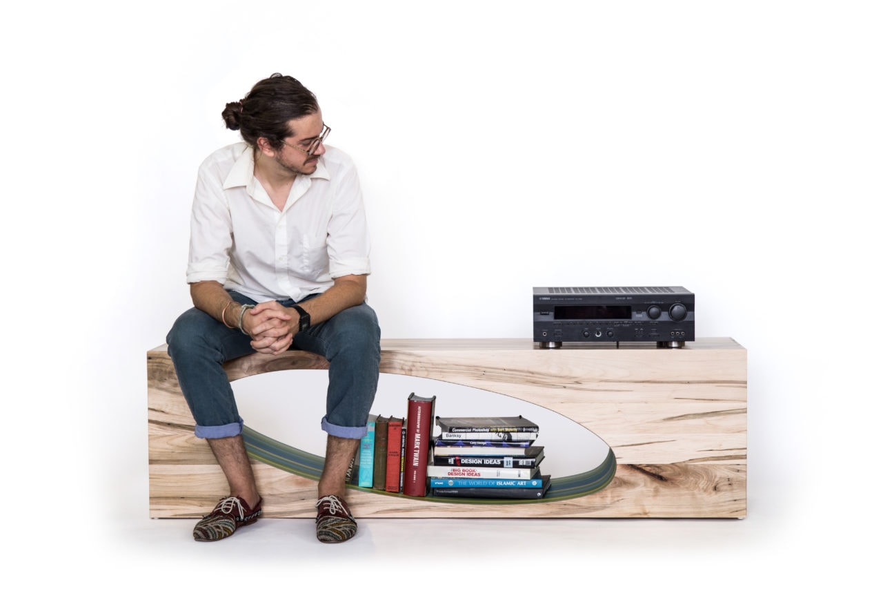 Man sitting atop a SENTIENT contemporary low Orbit coffee table with oval cutout 