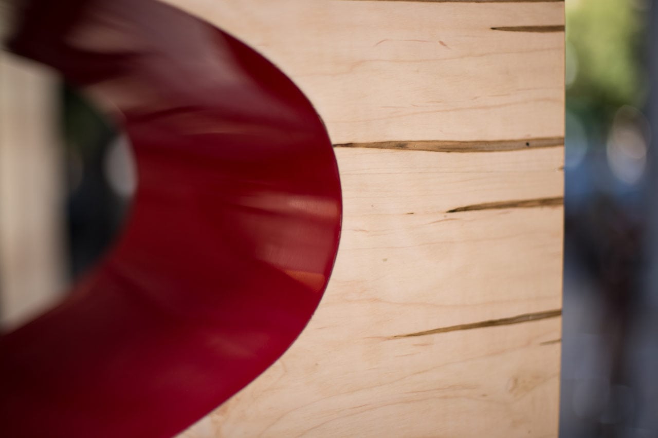a SENTIENT contemporary custom Orbit coffee table detail in maple with red colored oval cutout