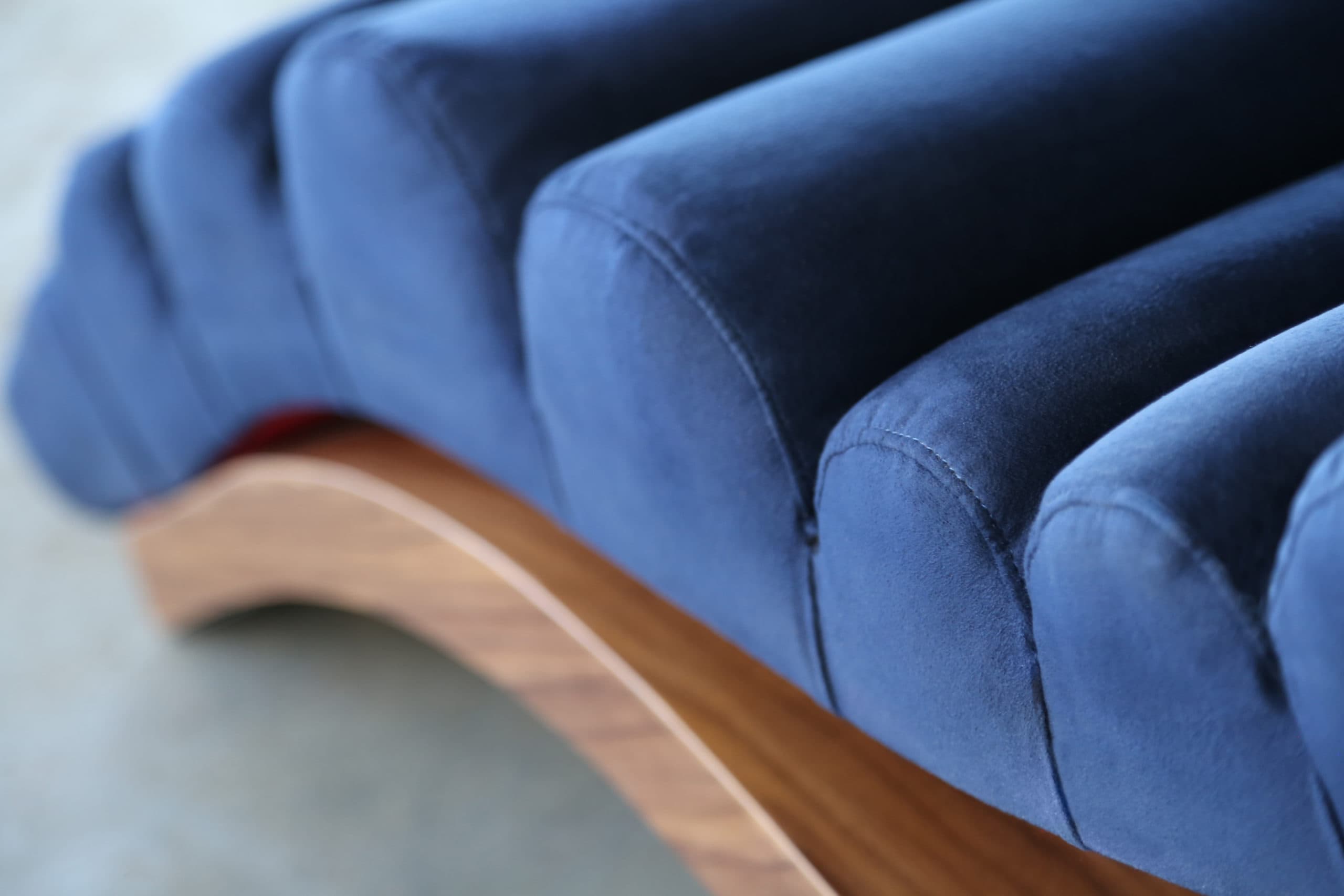 a SENTIENT contemporary designed custom wave lounge chair detail in luxury blue velvet with walnut base 