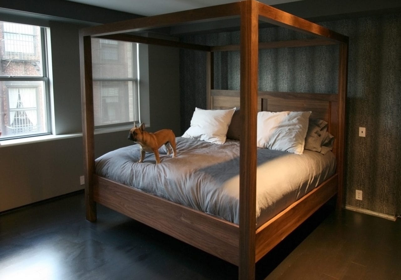 a custom walnut SENTIENT contemporary designed four poster bed in room with luxury bedding and puppy