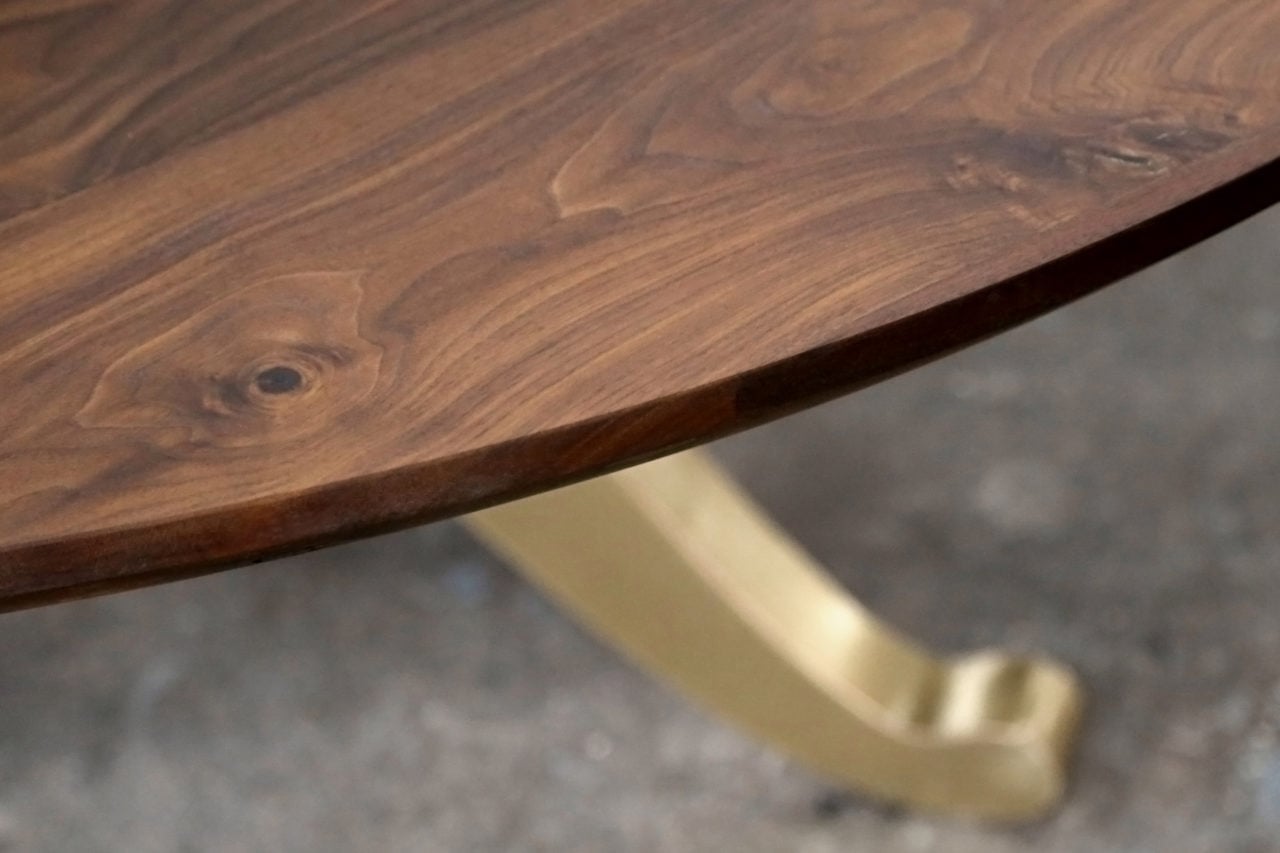 a SENTIENT contemporary designed custom round walnut dinning table with luxury brass wishbone leg detail view