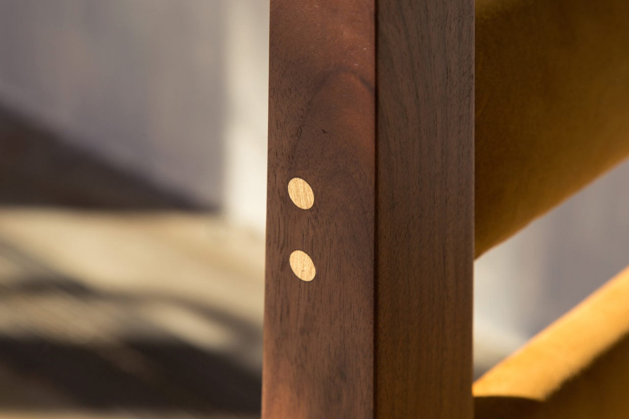 a SENTIENT contemporary designed custom dc-1 chair in walnut with detail of brass joint pegs