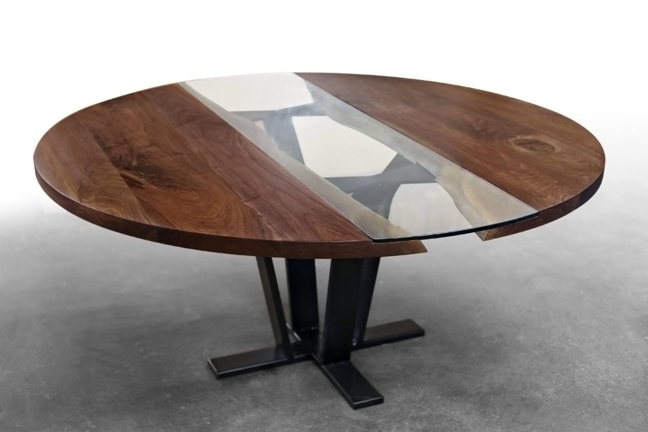 a SENTIENT contemporary designed custom round walnut table with inset glass and blackened steel v shaped leg 