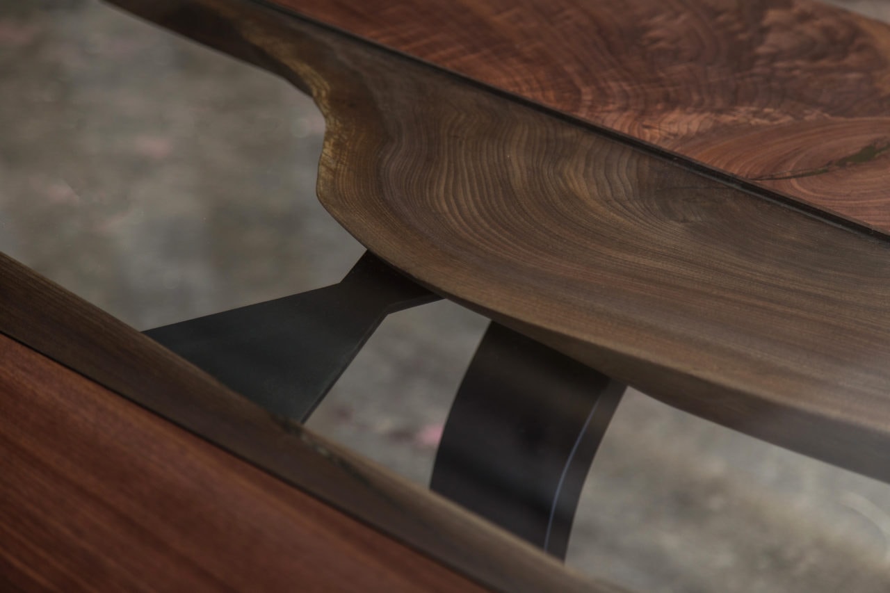 a SENTIENT contemporary designed custom round walnut table with inset glass and blackened steel v shaped leg detail view