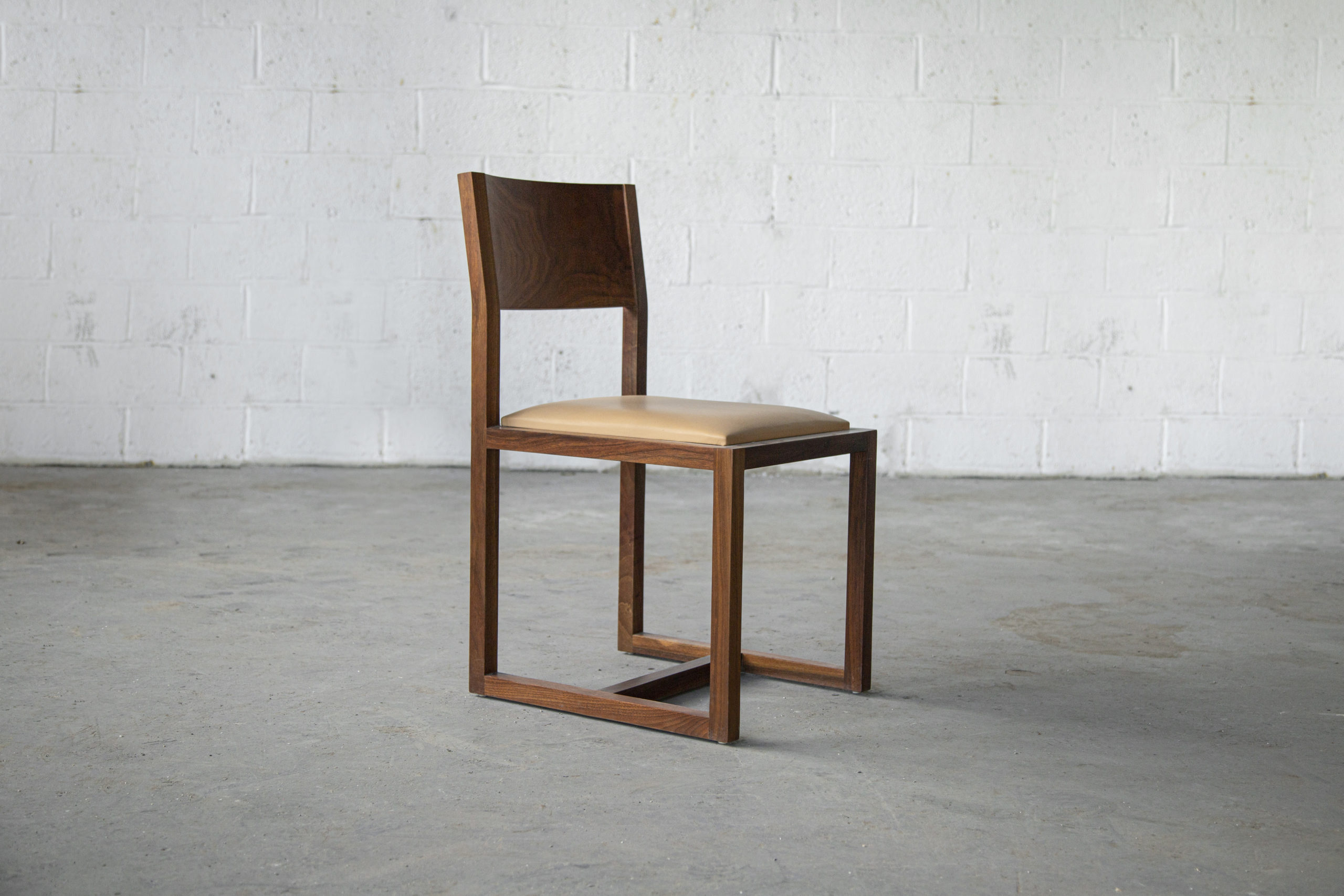 a contemporary designed SENTIENT Saint Lawrence custom dining chair of walnut and luxury leather seat front view