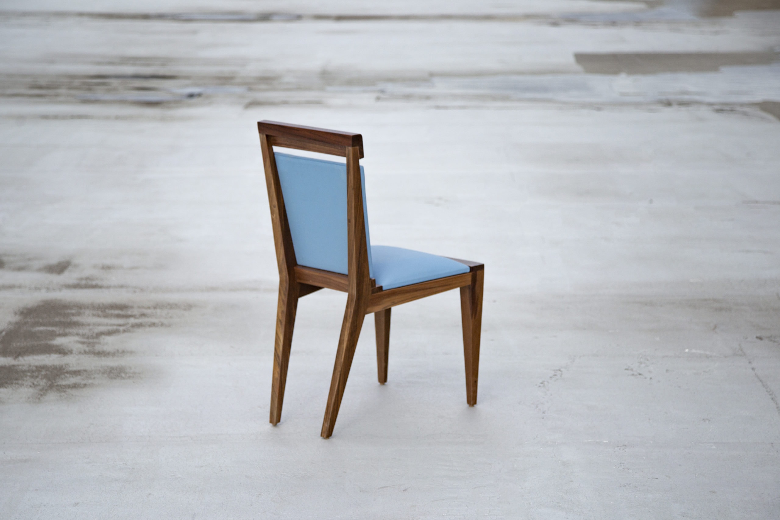 SENTIENT contemporary designed Angles dining chair in walnut with custom light blue leather upholstery, back view with grey background