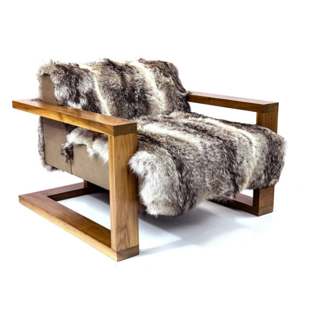 SENTIENT Furniture's Caribou luxury Lounge features a wooden frame with a unique horizontal bar design, draped in a luxurious faux fur throw, combining rustic elements with modern comfort.