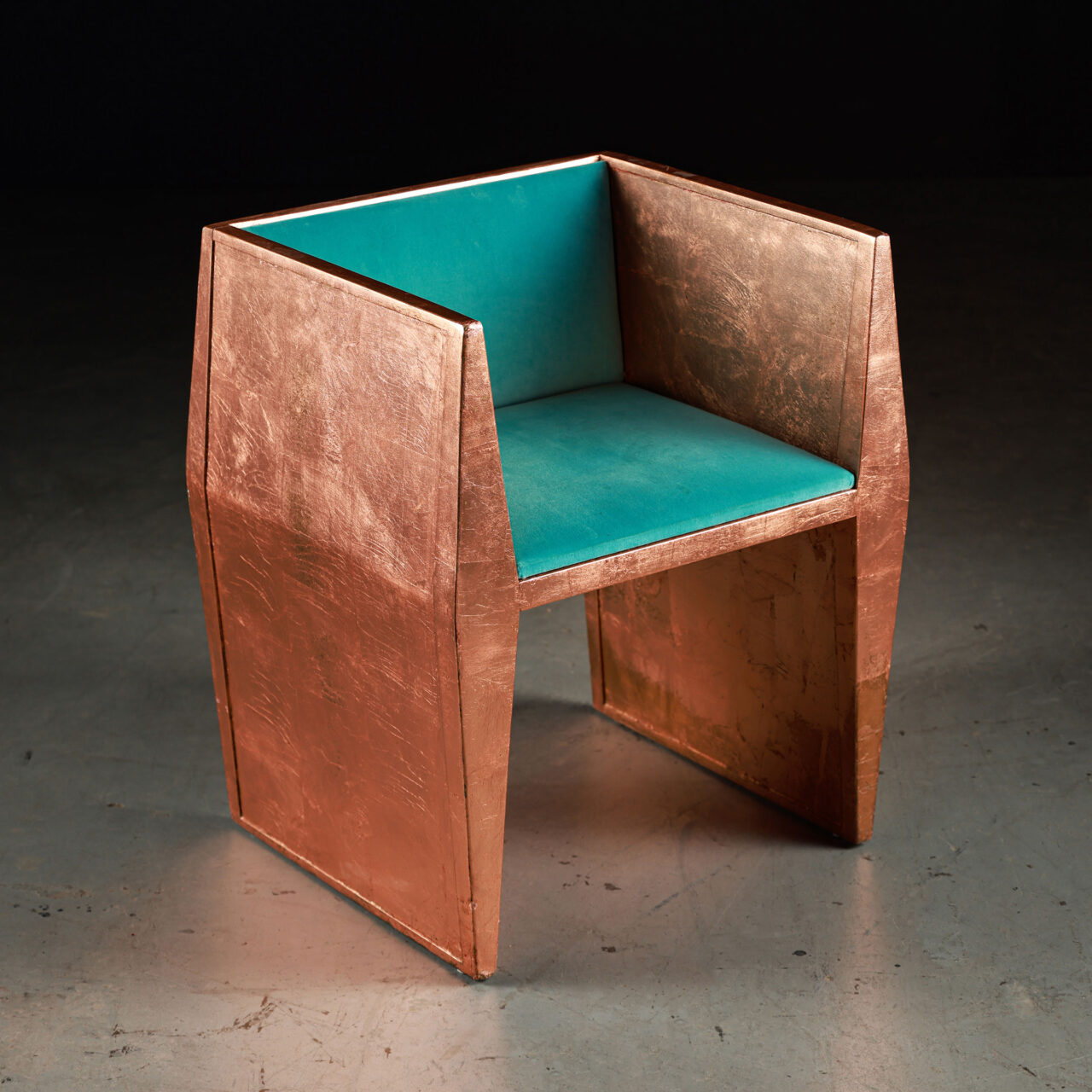 wooden unique chairs - a striking SENTIENT Sapience chair crafted with a hammered copper finish, featuring a geometric silhouette that exudes an industrial yet refined vibe. The chair is fitted with a plush teal cushion, providing a comfortable seating experience and a visual contrast that accentuates the chair's bold design.