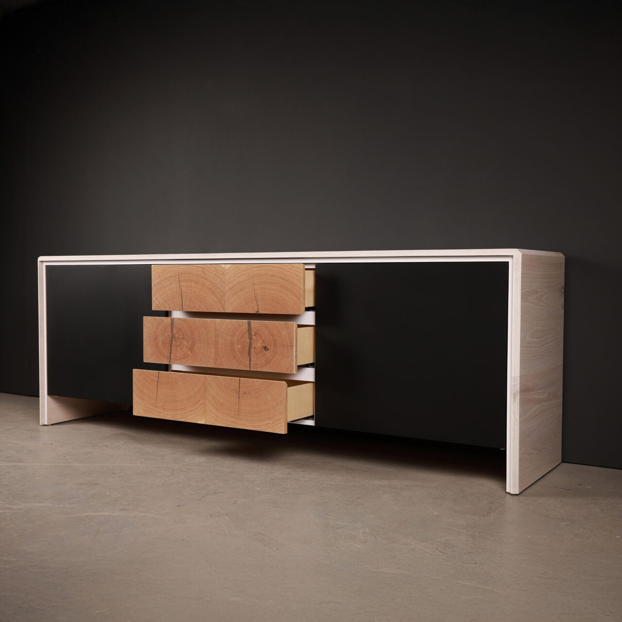 Minimalist credenza featuring a white frame and three natural wood drawers with a log-cut design, highlighting organic textures and modern craftsmanship.