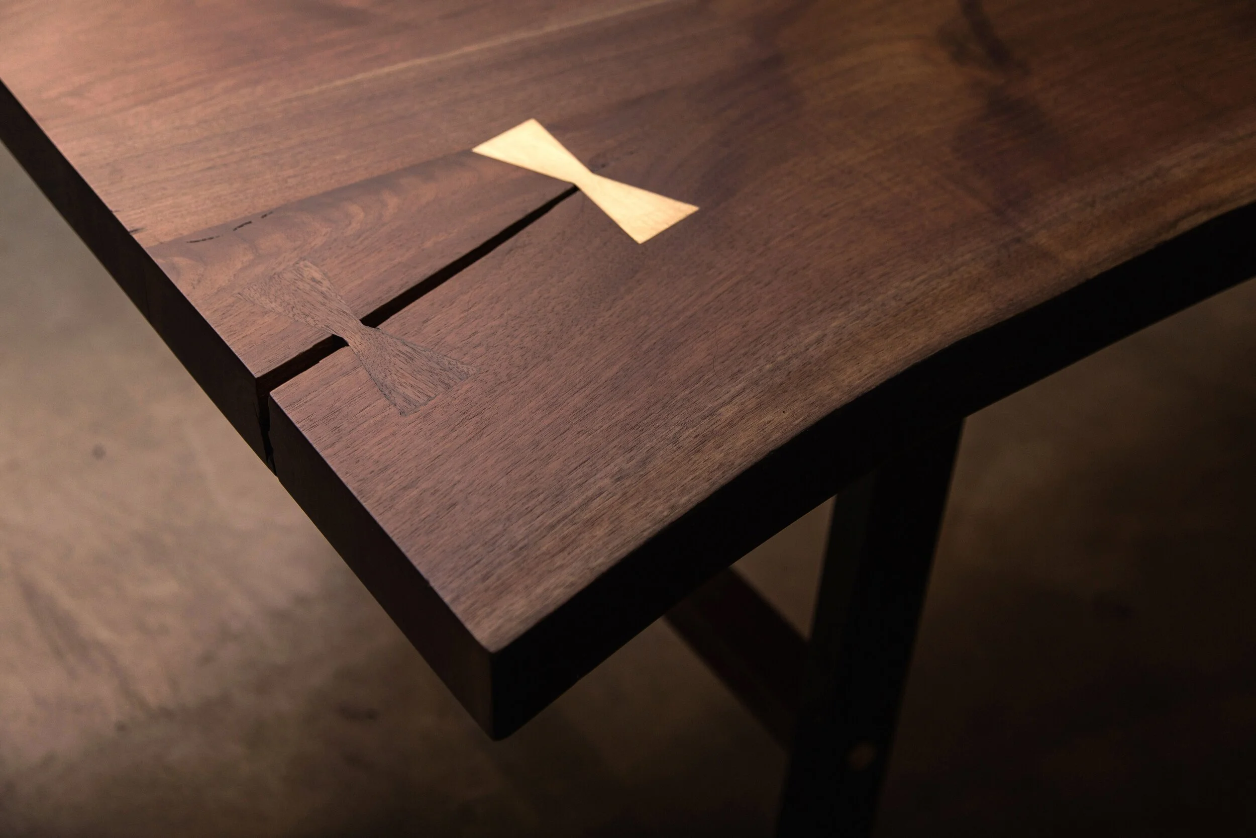 A Detail Of A SENTIENT Signature Live Edge Table With Two Butterfly Inlays In Wood And Brass