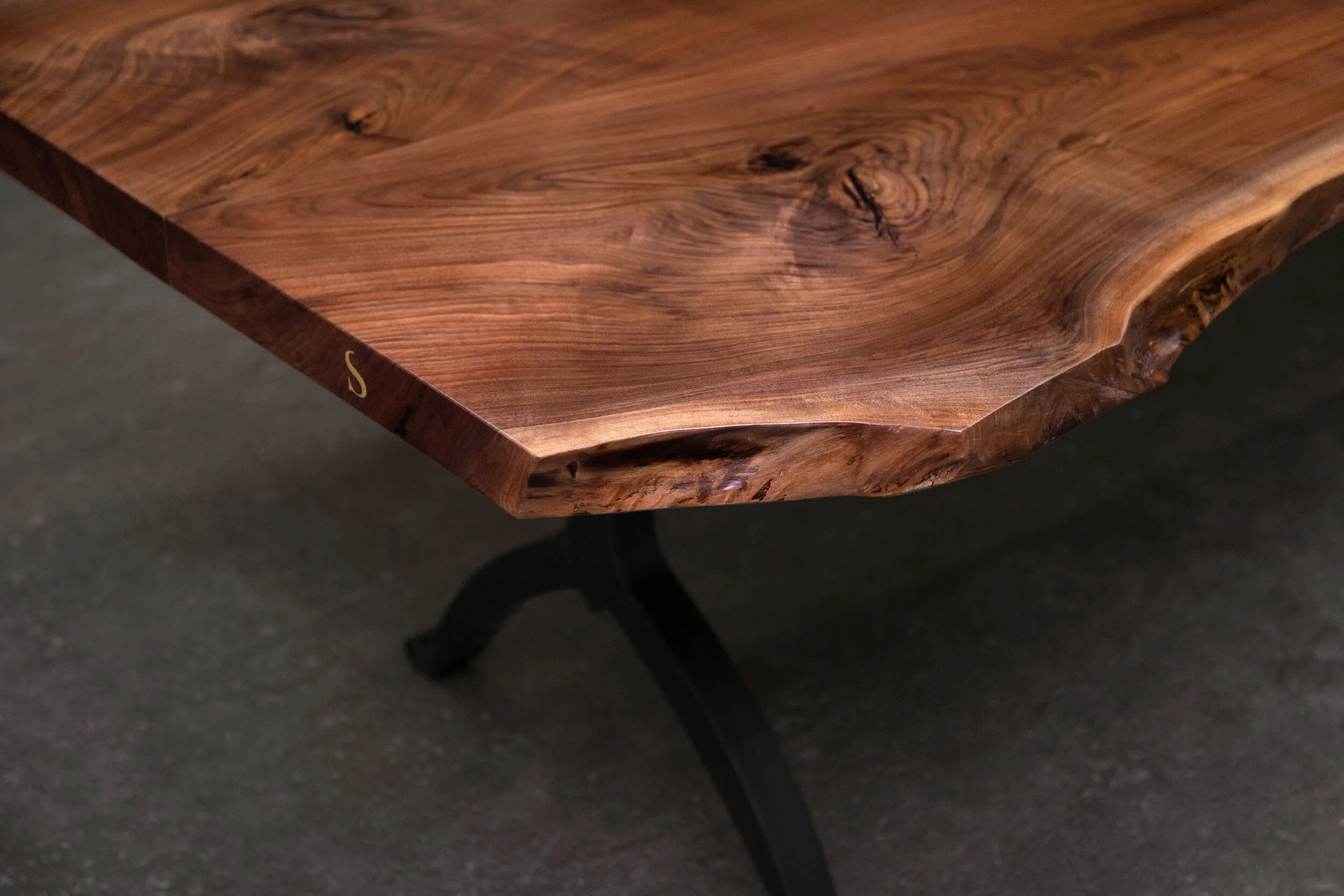 A SENTIENT Signature Live Edge Table In Walnut With Inlayed Brass “S” And Blackened Steel Wishbone Base